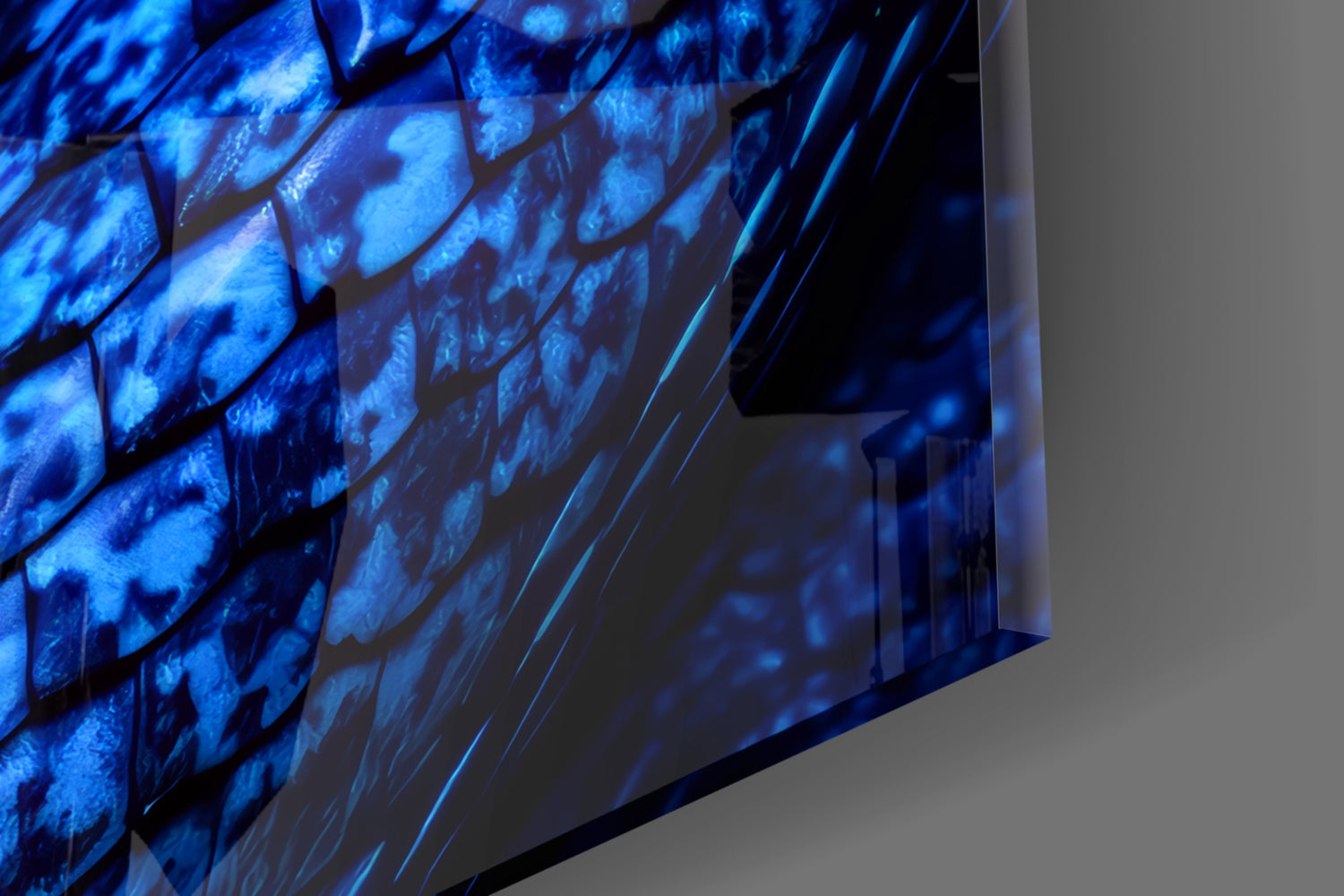 Close-up angle of illuminated blue glass wall art displaying scaled texture pattern against neutral background.