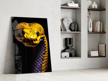 Golden and purple snake head glass wall art leaning against white wall beside wooden shelving unit with decorative objects.