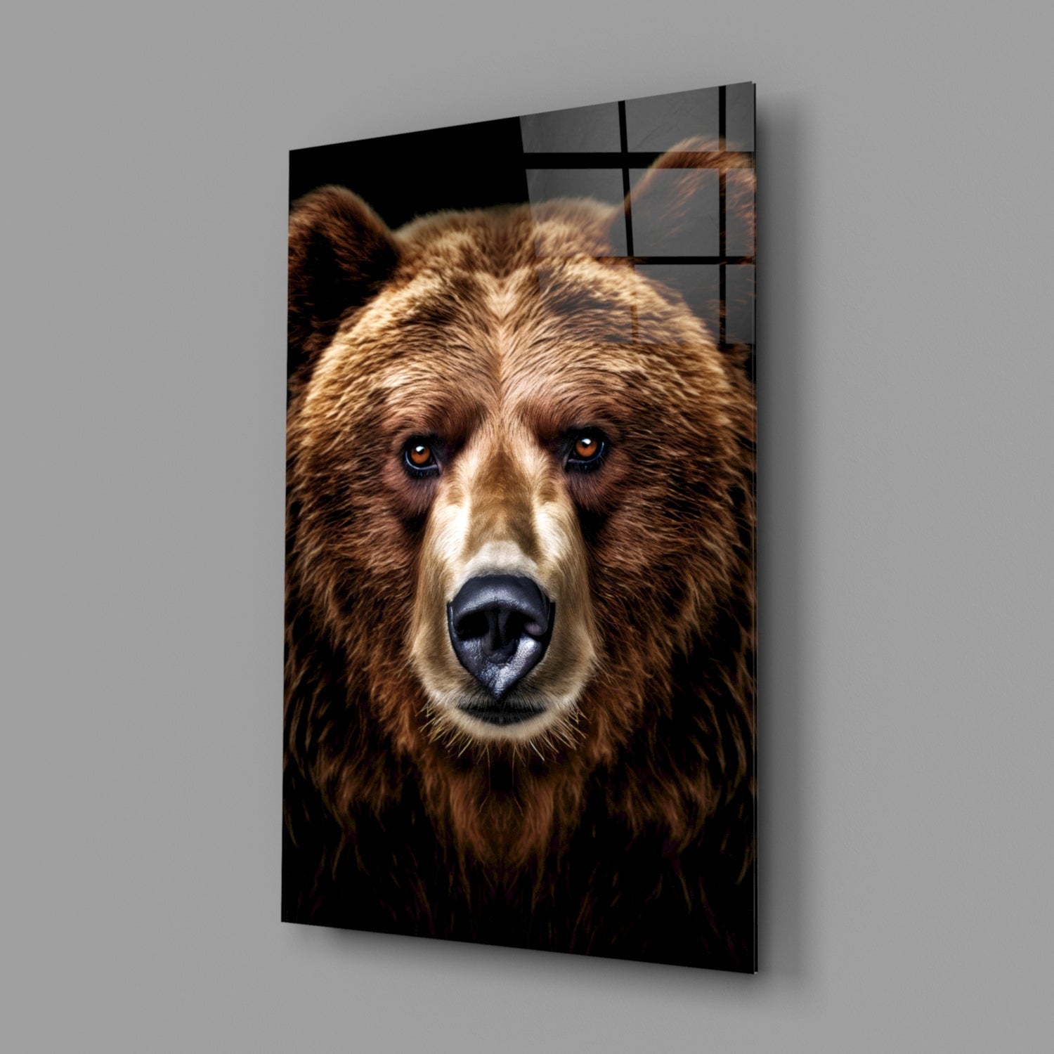 Brown bear's front-facing portrait with blue eyes on black background, displayed as angled glass wall art panel.