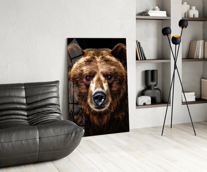Bear glass wall art featuring a brown bear's face with blue eyes displayed in a modern living room beside a gray chair and shelving unit.