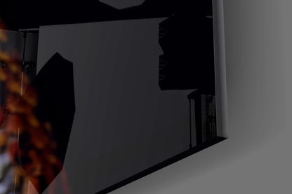 Dark silhouette of glass wall art installation mounted on gray wall with fiery orange glow visible on left edge.