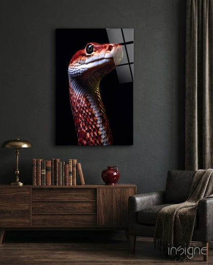 Red and white serpent head in profile against black background, displayed on dark gray wall above wooden cabinet in styled room setting.