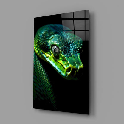 Angled perspective of glass wall art displaying vibrant green viper head against black background with grid overlay.