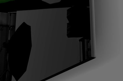 Silhouetted view of dark glass wall art panel mounted on light gray wall with studio lighting setup visible.
