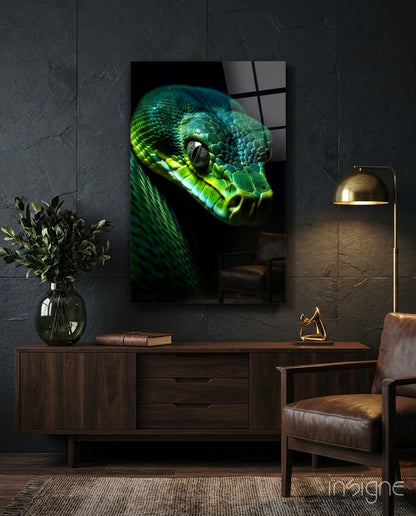 Emerald green viper glass wall art displayed above a wooden sideboard in a dark modern interior with leather chair and brass lamp.