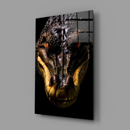 Close-up front view of glass wall art featuring a crocodile's head with glowing orange eyes and yellow jaw against black background.