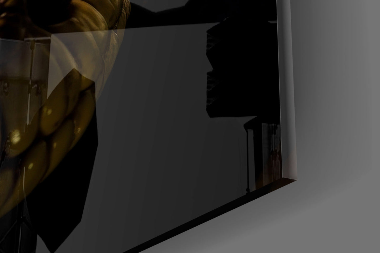 Close-up angled view of glass wall art showing dark silhouette profile and metallic gold frame detail against white wall.