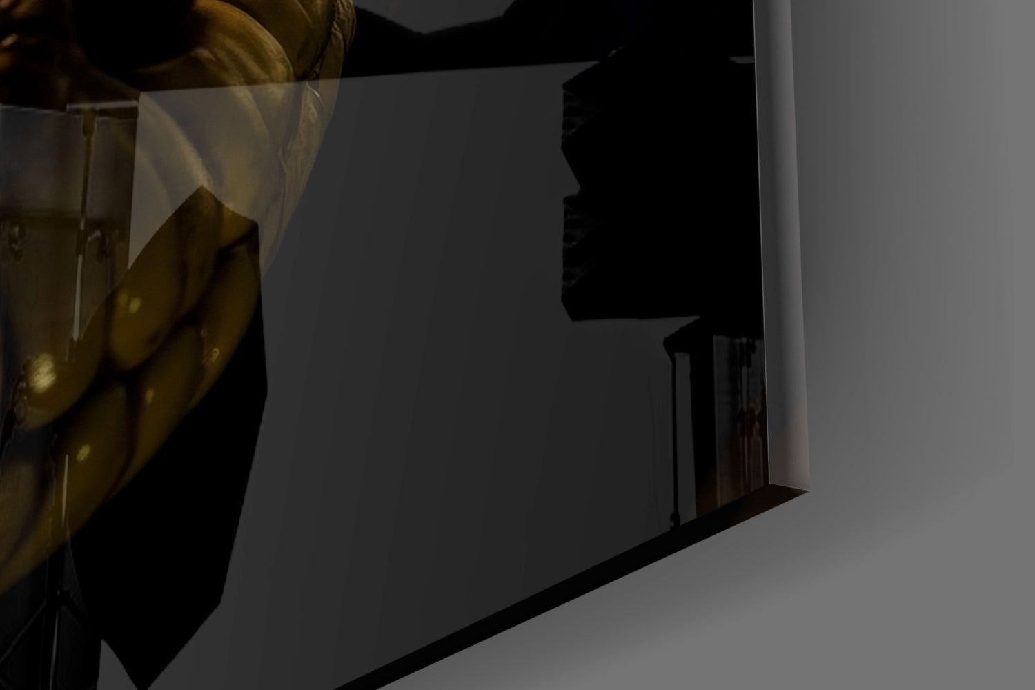 Close-up angled view of glass wall art showing dark silhouette profile and metallic gold frame detail against white wall.