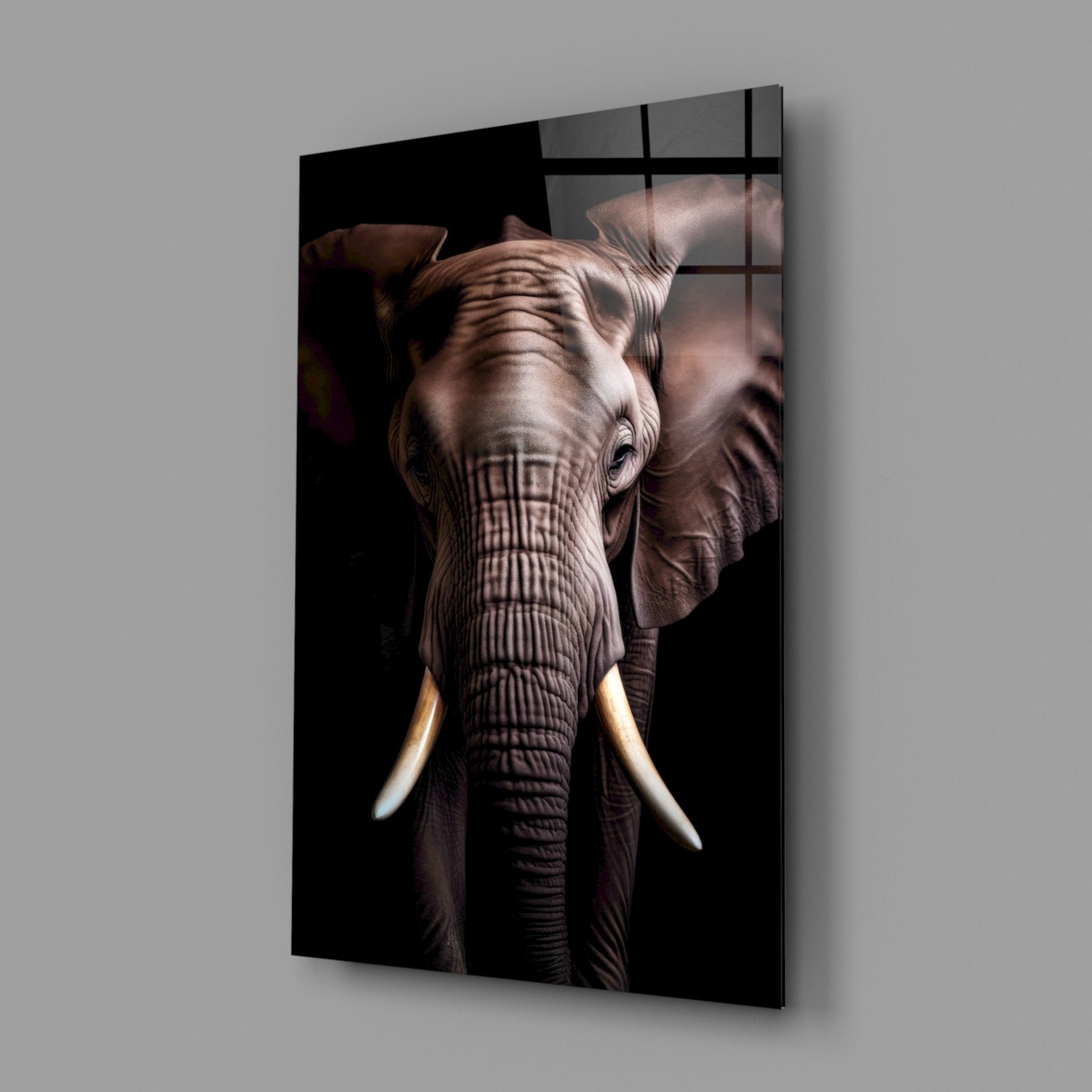 Angled view of glass wall art displaying a detailed elephant head with ivory tusks against black background, mounted on gray wall.
