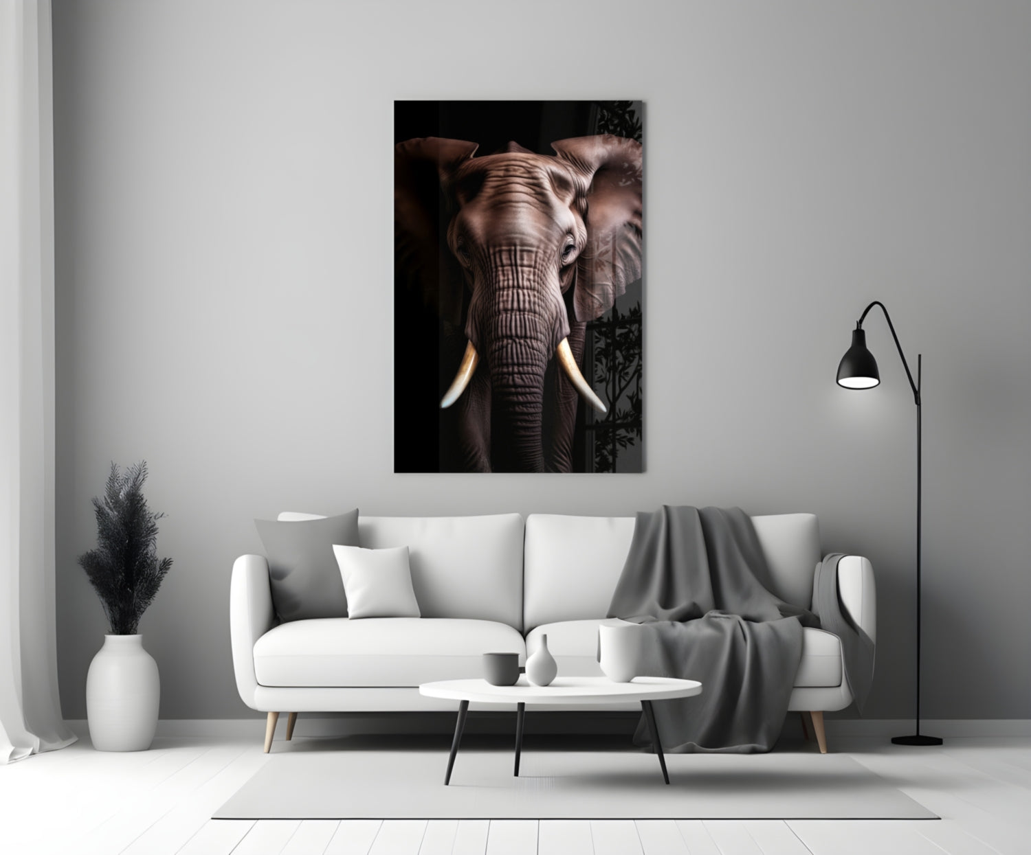 Elephant glass wall art displaying a frontal close-up of an elephant's face with ivory tusks against a black background, hung above a white sofa in a modern living room.