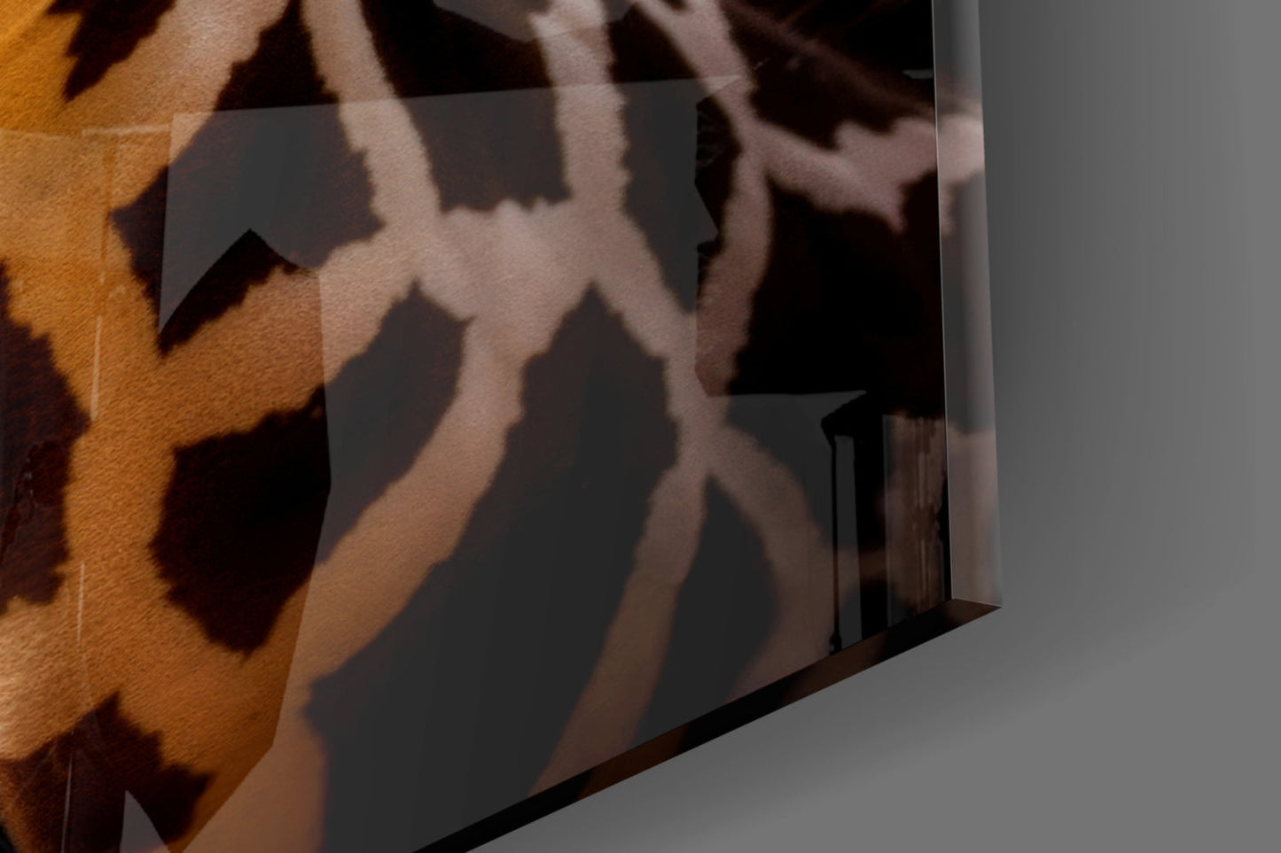 Close-up angled view of translucent glass panel displaying giraffe silhouettes in warm brown and tan tones against gray wall.