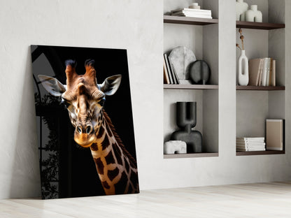 Giraffe glass wall art leaning against white wall beside shelving unit displaying books and decorative objects.