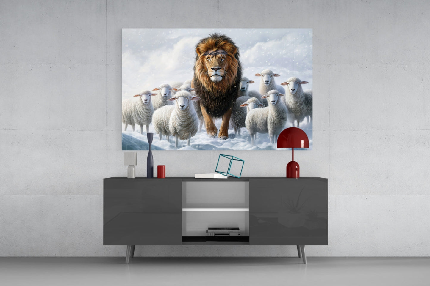 Glass wall art depicting a lion surrounded by white sheep in a snowy landscape, displayed above a dark modern console table with red decorative accessories.