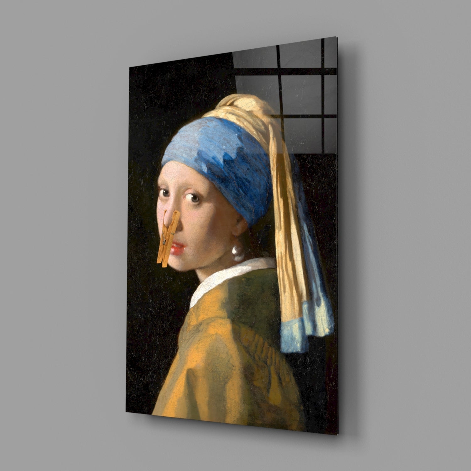 Glass wall art depicting a young woman in profile wearing a blue headwrap and golden earring against a dark background.