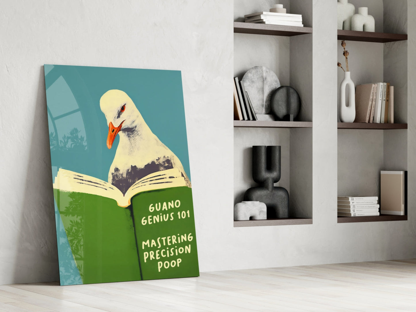 Humorous glass wall art leaning against white wall featuring illustrated seagull reading green book titled "Guano Genius 101: Mastering Precision Poop" on turquoise background.