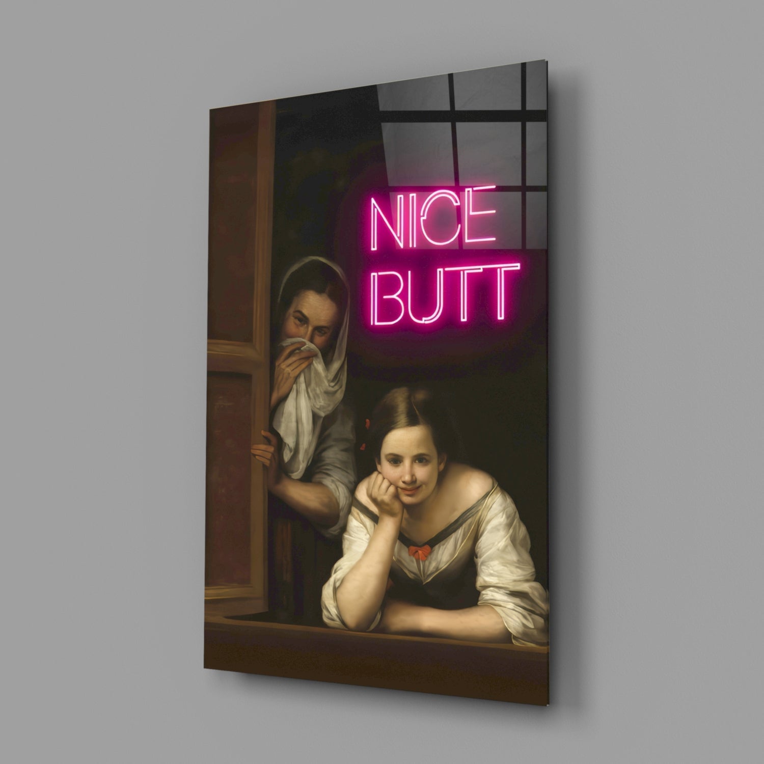 Angled product shot of glass wall art displaying classical painting of two women at a window with bright pink neon "NICE BUTT" text overlay.