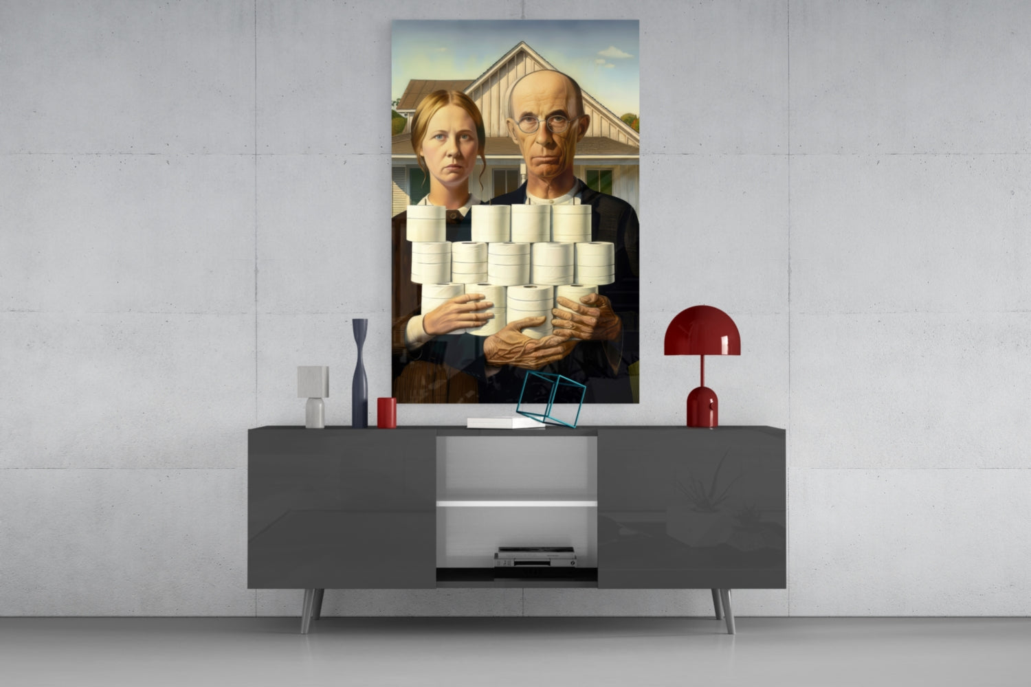 Glass wall art displaying two figures holding toilet paper rolls, mounted above a gray console table in a modern interior setting.