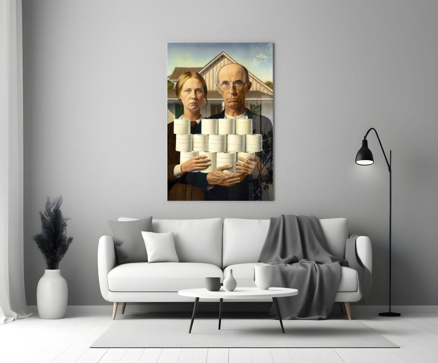 Modern living room with white sofa displaying glass wall art featuring two figures holding white cylindrical objects against farmhouse background.