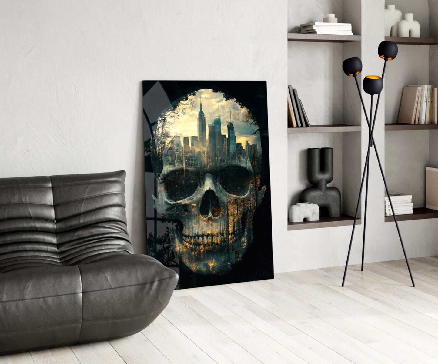 City skull glass wall art leaning against white wall in modern living room with grey sofa and shelving.