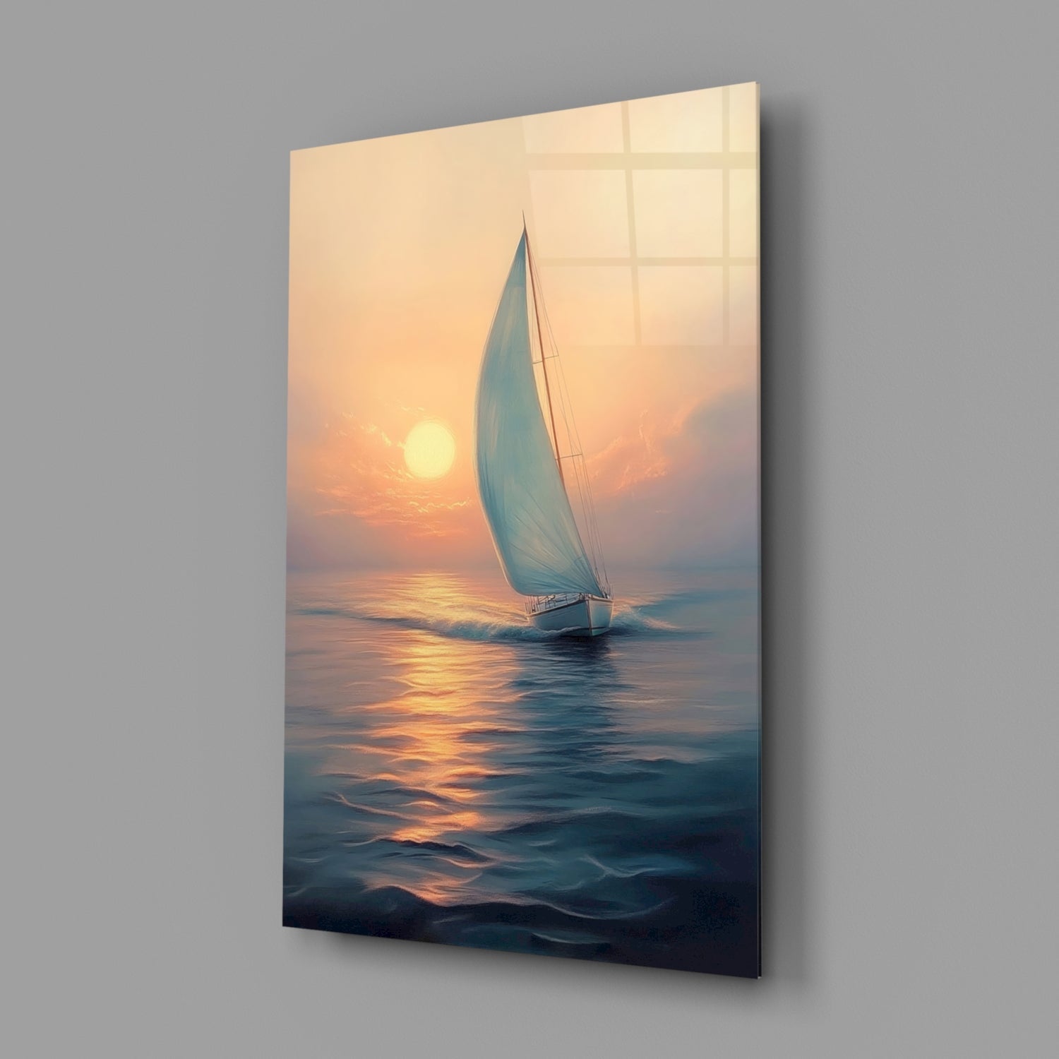 Angled view of glass wall art displaying a white sailboat on golden sunset waters against a warm peachy sky.