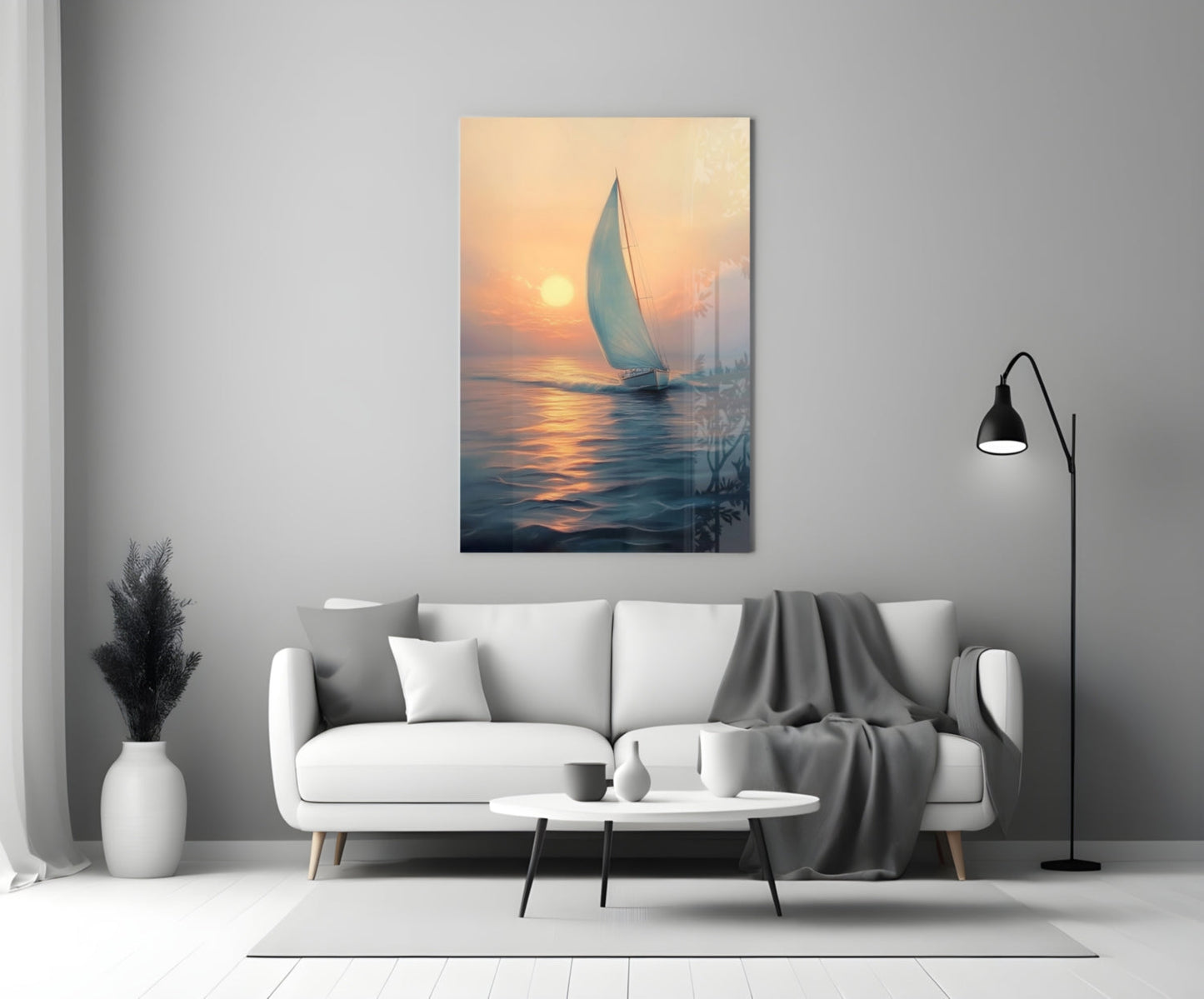 Sailboat glass wall art hanging above white sofa, depicting golden sunset over calm water with coastal cityscape silhouette.