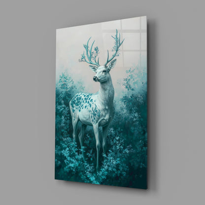 Angled view of glass wall art displaying a white deer with turquoise antlers surrounded by teal foliage against a gradient background.