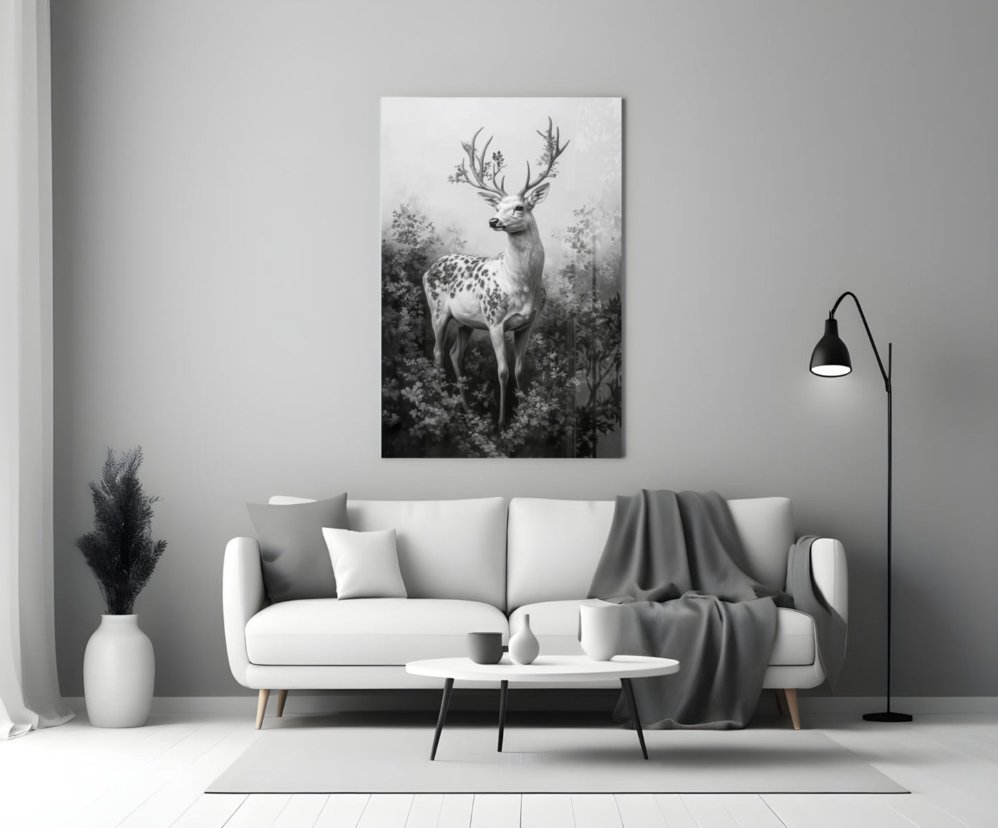 Monochrome glass wall art depicting a spotted deer with antler branches displayed above a white sofa in a minimalist interior.