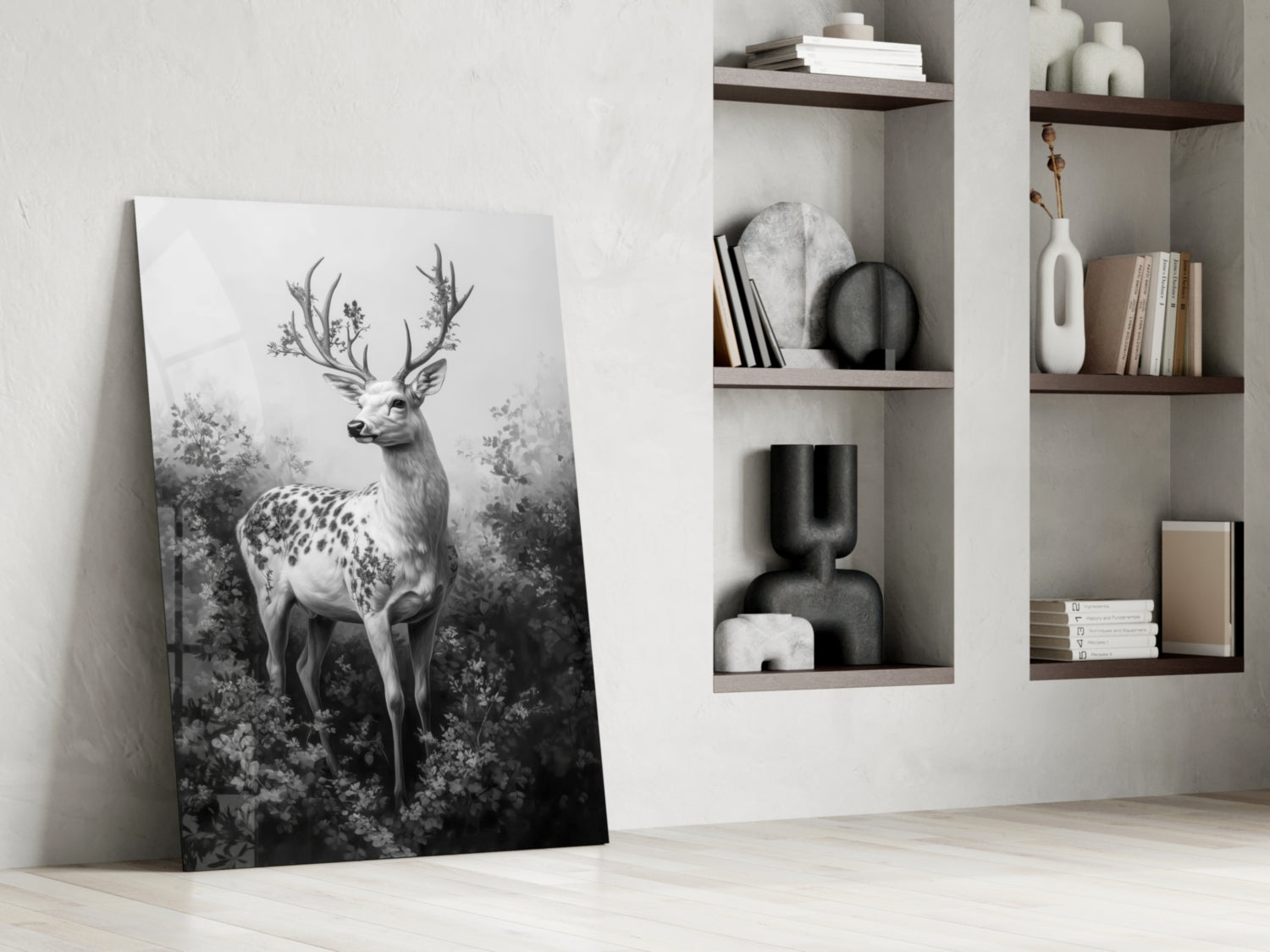 Monochrome glass wall art leaning against white wall displays detailed deer with antlers in forest setting, positioned beside built-in shelving with decorative objects.