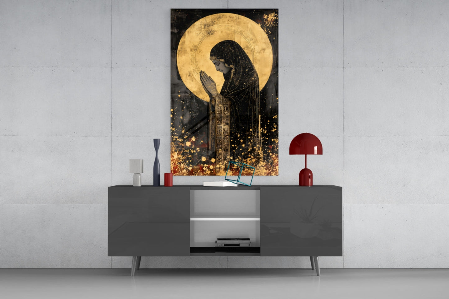 Golden Prayers of Mary glass wall art displayed above a dark gray media console with red decorative lamps and accessories.