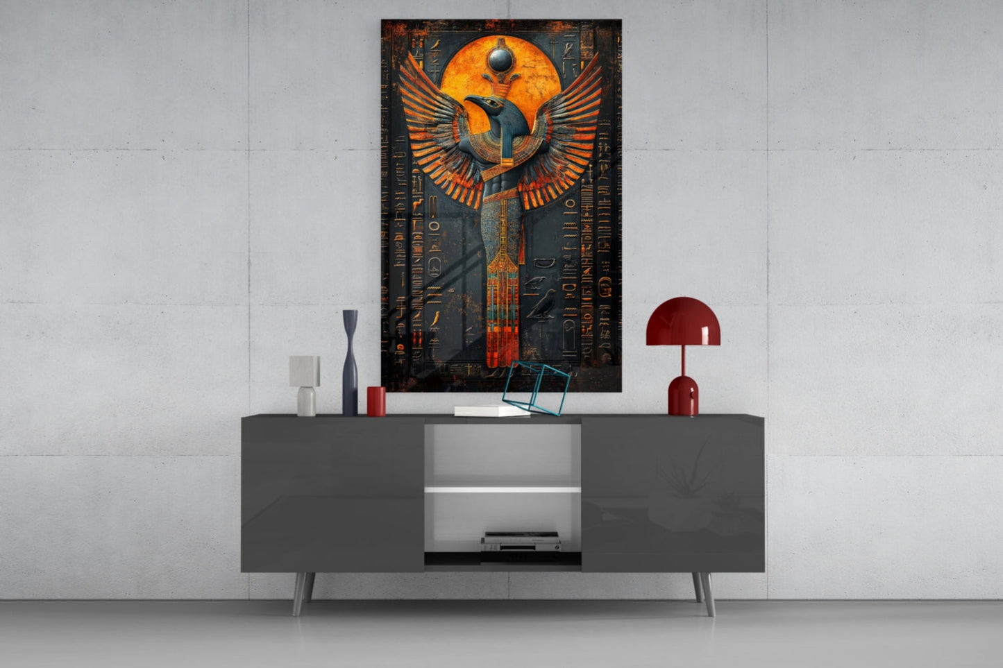 Egyptian winged deity glass art with orange and gold wings displayed above gray media console in modern interior setting.