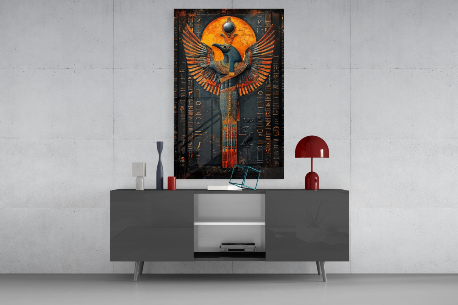 Egyptian winged deity glass art with orange and gold wings displayed above gray media console in modern interior setting.