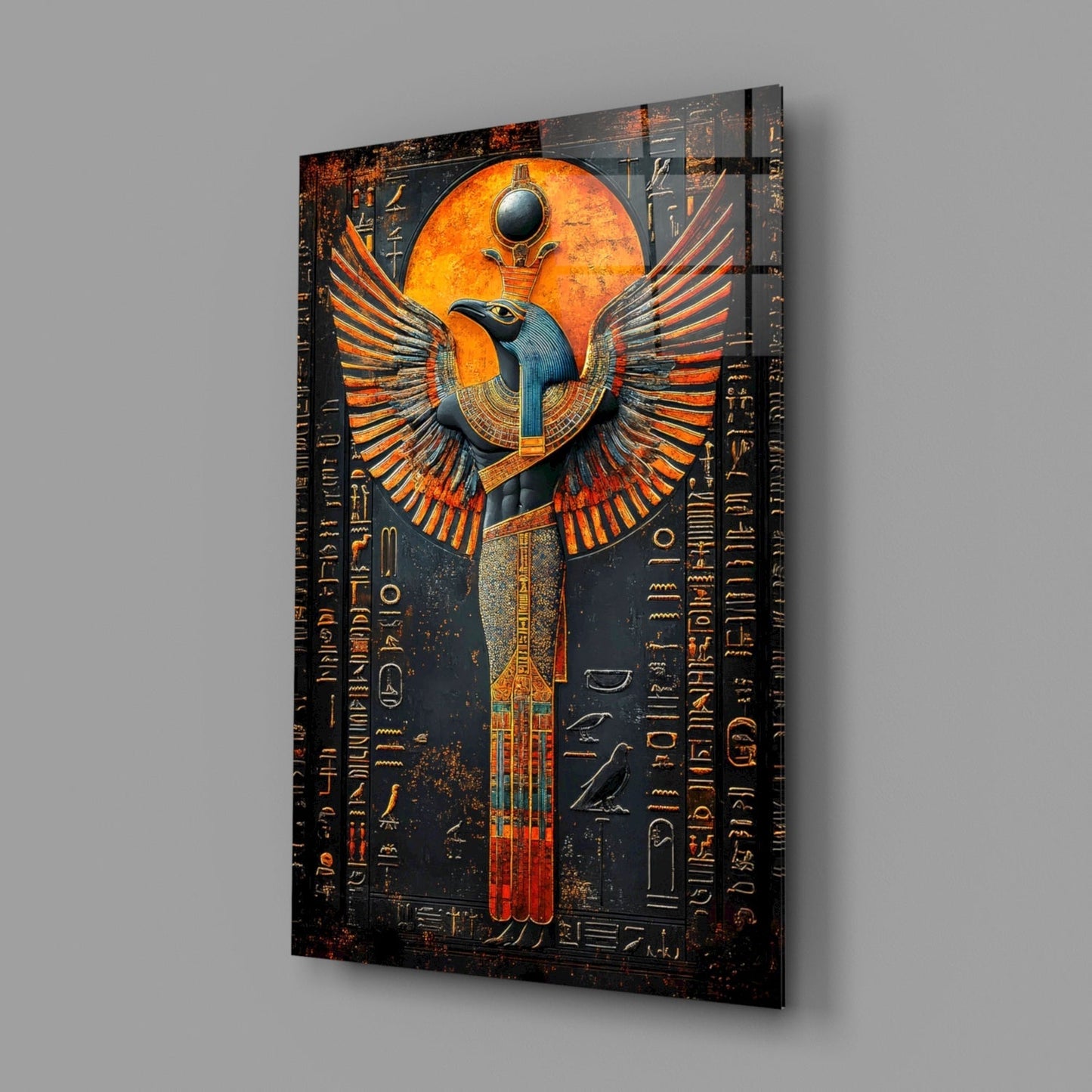 Angled perspective view of glass wall art featuring an Egyptian winged deity with orange and blue coloring against dark background with hieroglyphic text.