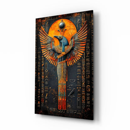 Angled view of glass wall art depicting an Egyptian winged deity with orange and blue coloring against dark background with hieroglyphic text.