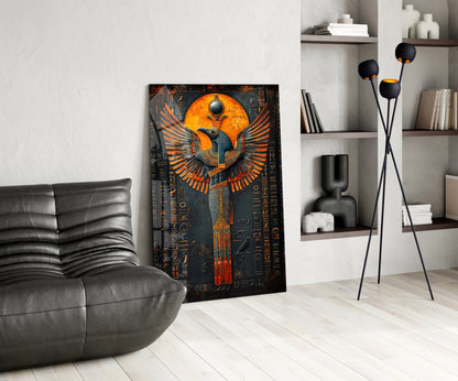 Egyptian winged deity glass art leaning against white wall in modern living room with gray leather chair and shelving.