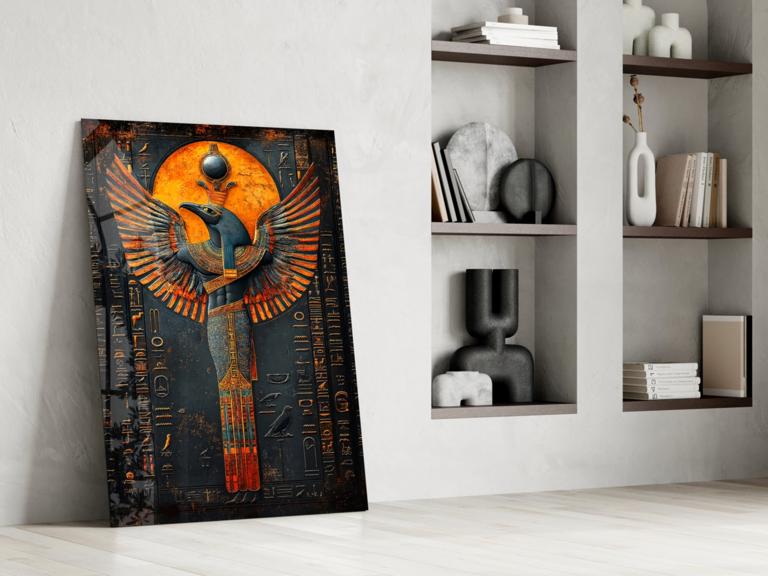 Egyptian winged deity glass art leaning against white wall beside built-in shelving with decorative objects.