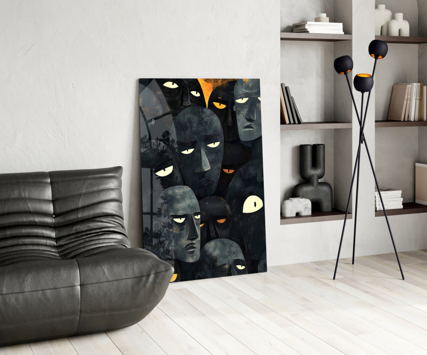 Dark glass wall art featuring multiple abstract faces with glowing yellow and orange eyes, displayed in modern living room beside gray leather sofa.