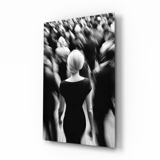 Black and white glass wall art showing a solitary figure in dark clothing surrounded by blurred crowd silhouettes.