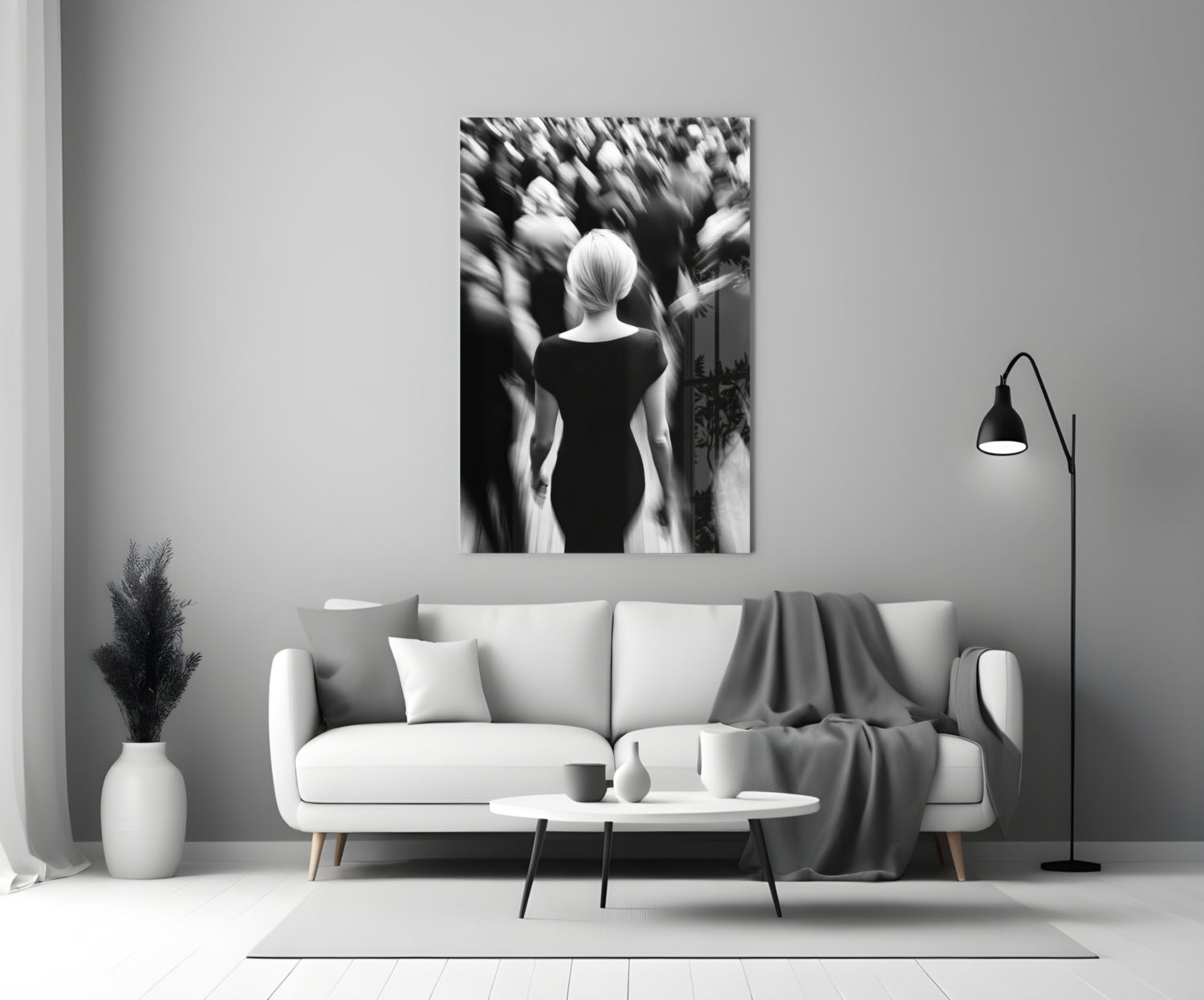 Black and white glass wall art depicting a solitary figure viewed from behind amid a blurred crowd, displayed above a white sofa in a minimalist living room setting.
