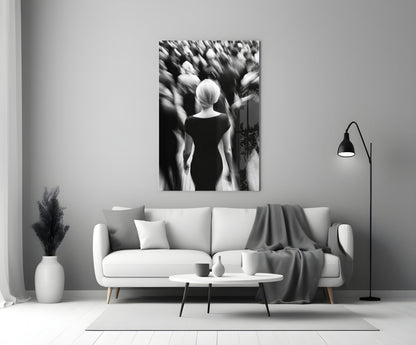 Black and white glass wall art depicting a solitary figure viewed from behind amid a blurred crowd, displayed above a white sofa in a minimalist living room setting.