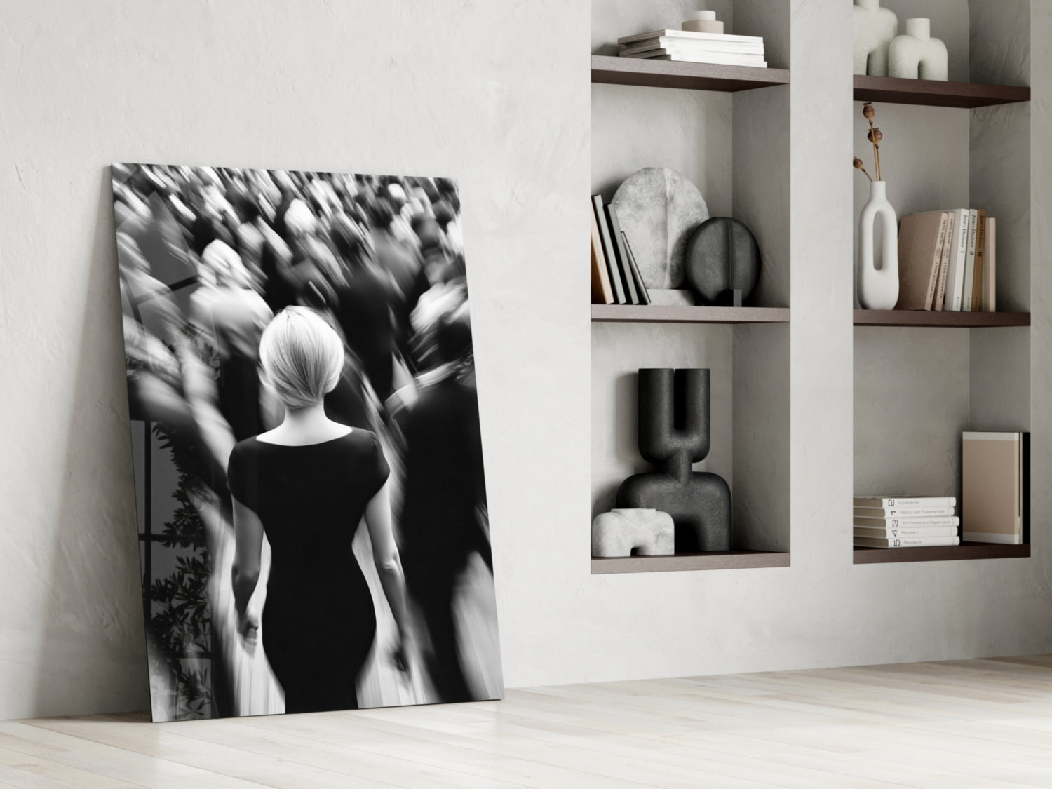 Black and white glass wall art leaning against white wall beside shelving unit displaying decorative objects and books.