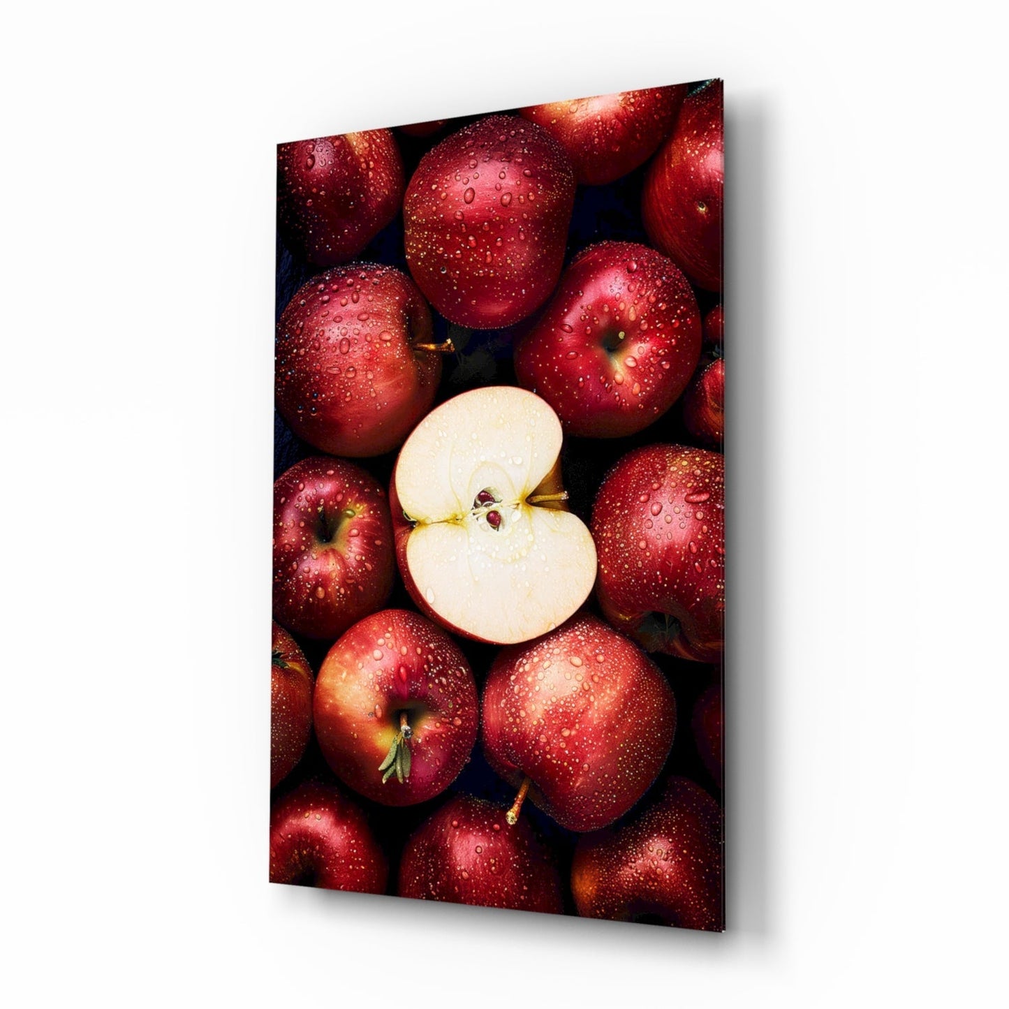 Red apples with water droplets surrounding one sliced apple half, displayed on glass wall art with dark background.
