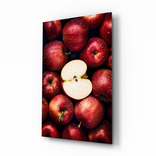Red apples with water droplets surrounding one sliced apple half, displayed on glass wall art with dark background.