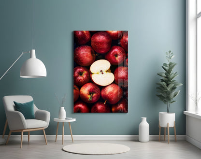 Red apples with a sliced apple center displayed on glass wall art in a modern interior setting with teal walls and white furniture.