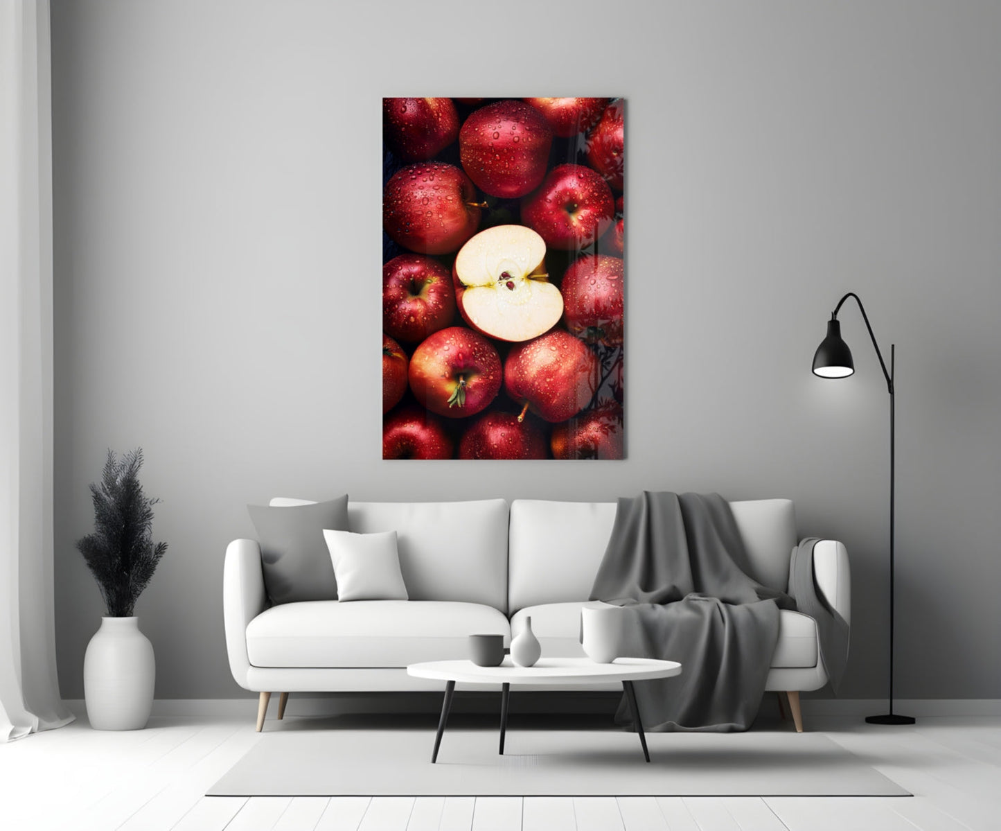 Glass wall art featuring red apples with one sliced apple in center, displayed above white sofa in modern living room.
