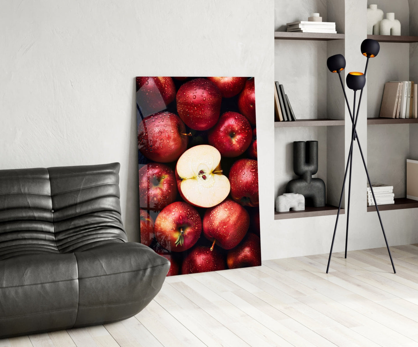 Modern living room with red apple glass wall art leaning against white wall beside gray sofa and black floor lamp.