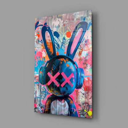 Angled view of glass wall art featuring a stylized rabbit head wearing blue headphones with pink X eyes against a vibrant multicolored graffiti background.
