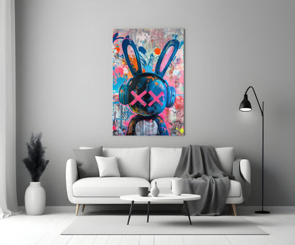 Colorful graffiti rabbit glass art with pink X eyes and headphones displayed above white sofa in modern living room.