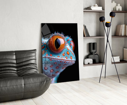 Modern living room interior featuring a vibrant glass wall art displaying a close-up reptile eye with orange iris and turquoise scaled head against black background.