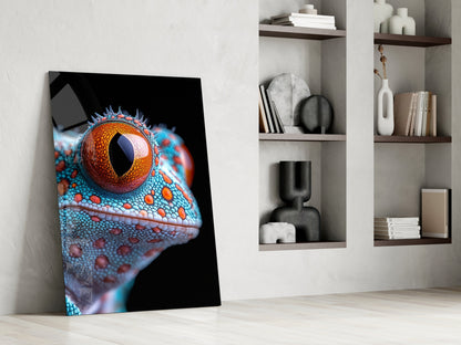 Vibrant glass art leaning against white wall displays close-up reptile eye with orange iris and turquoise textured skin on black background.
