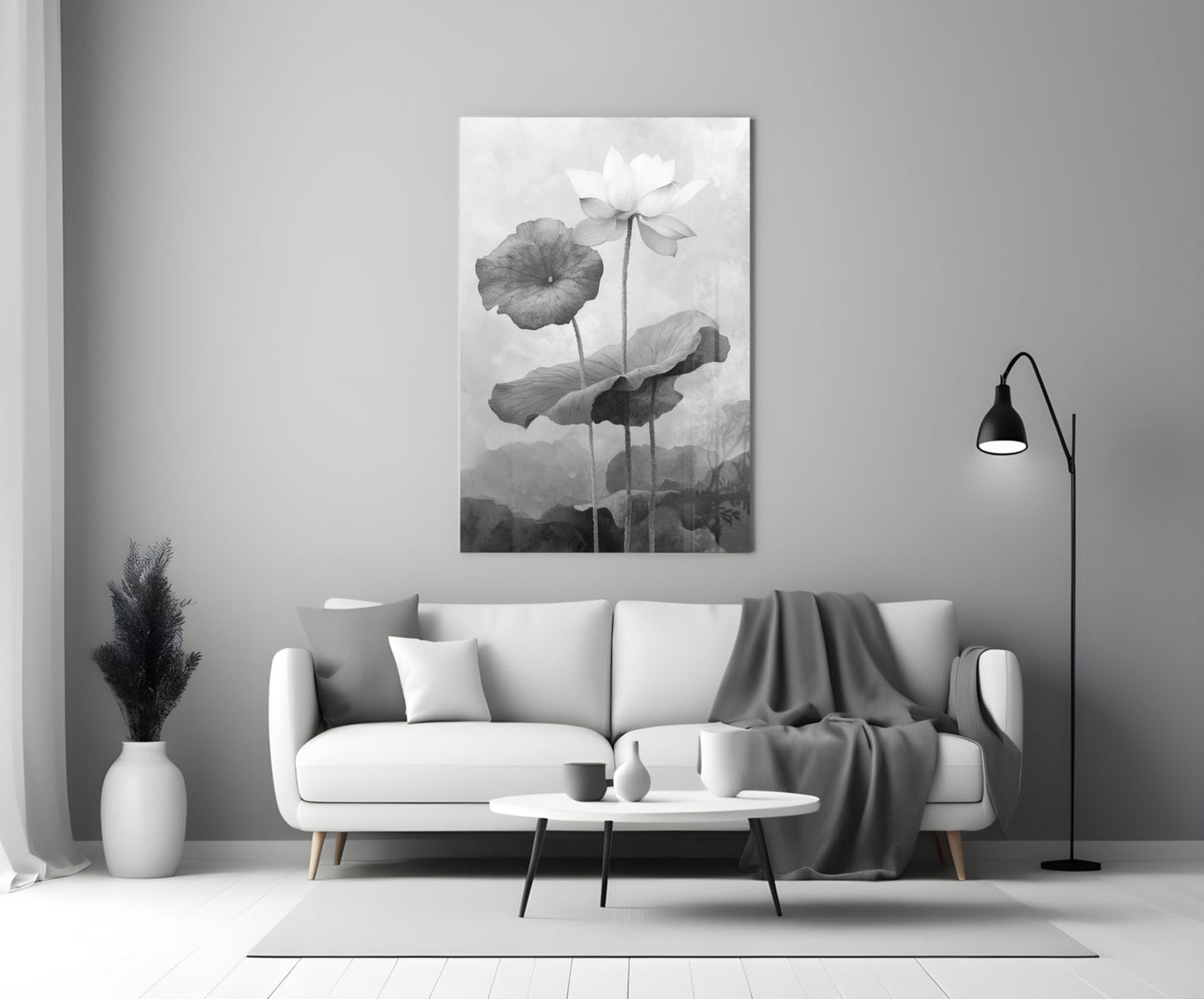 Black and white glass wall art depicting water lilies displayed above a white sofa in a minimalist living room setting.